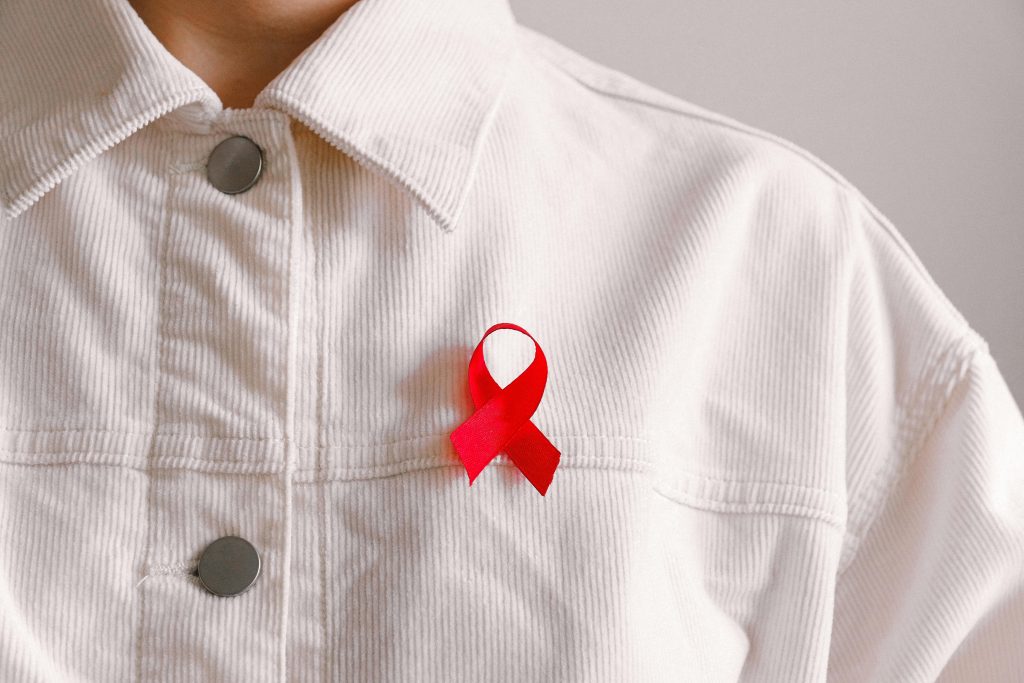 Red ribbon for HIV/AIDS awareness pinned on a white shirt symbolizing support and solidarity.
