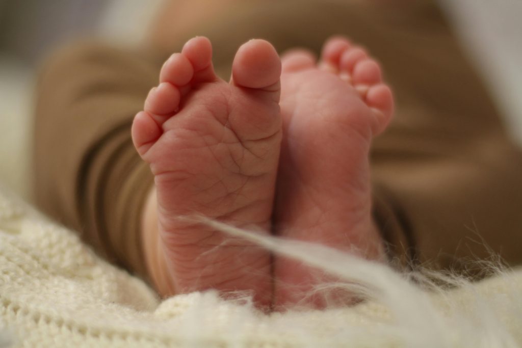Tender close-up photo of a newborn baby's tiny feet resting on a soft blanket.